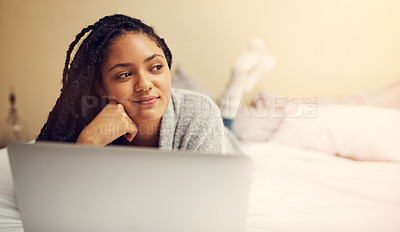 Buy stock photo Shot of a young woman using her laptop while lying in her bedroom