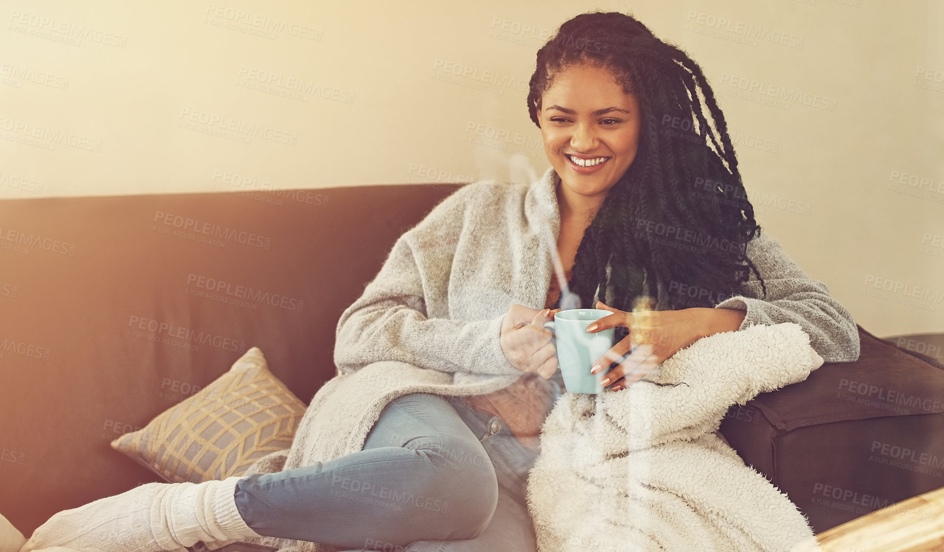 Buy stock photo Shot of a young woman enjoying a cup of coffee in her living room