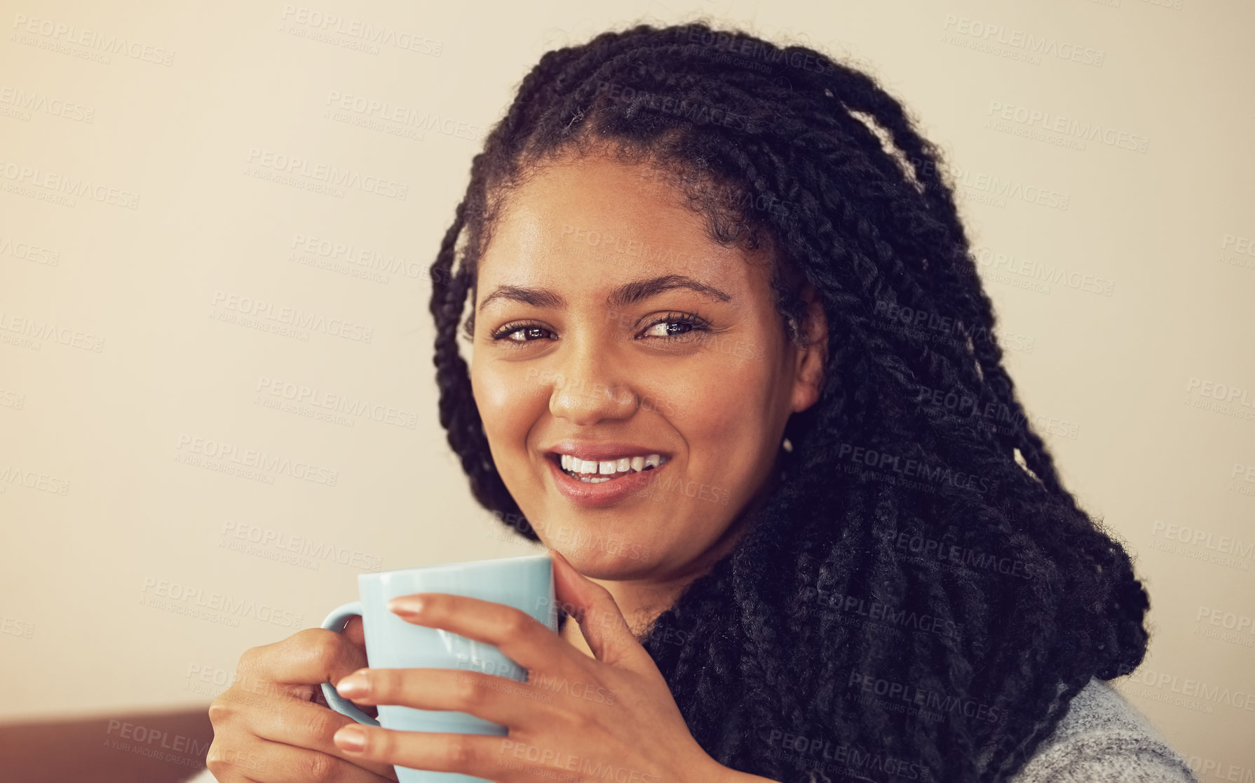 Buy stock photo Shot of a young woman enjoying a cup of coffee in her living room
