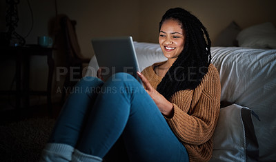 Buy stock photo Shot of a relaxed young woman using a digital tablet during the evening at home