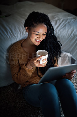 Buy stock photo Shot of a relaxed young woman drinking coffee and using a digital tablet during the evening at home