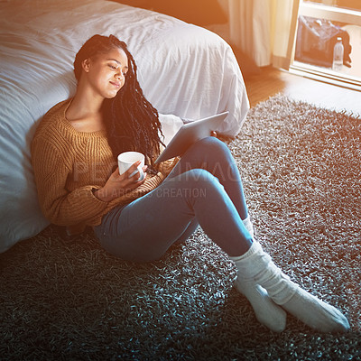 Buy stock photo Shot of a relaxed young woman drinking coffee and using a digital tablet at home