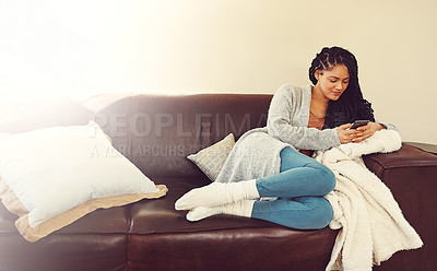 Buy stock photo Shot of a young woman using her phone while relaxing in her her living room