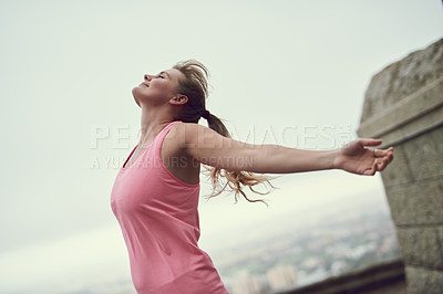 Buy stock photo Shot of a happy young woman feeling free while out for a run in the city