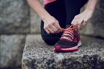 Buy stock photo Shot of an unidentifiable young woman tying her shoelace before a run in the city