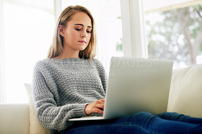 Buy stock photo Cropped shot of an attractive young woman using her laptop while chilling at home