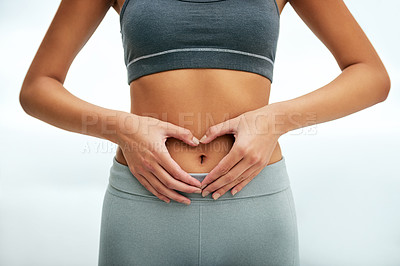 Buy stock photo Cropped shot of a woman forming a heart shape on her stomach