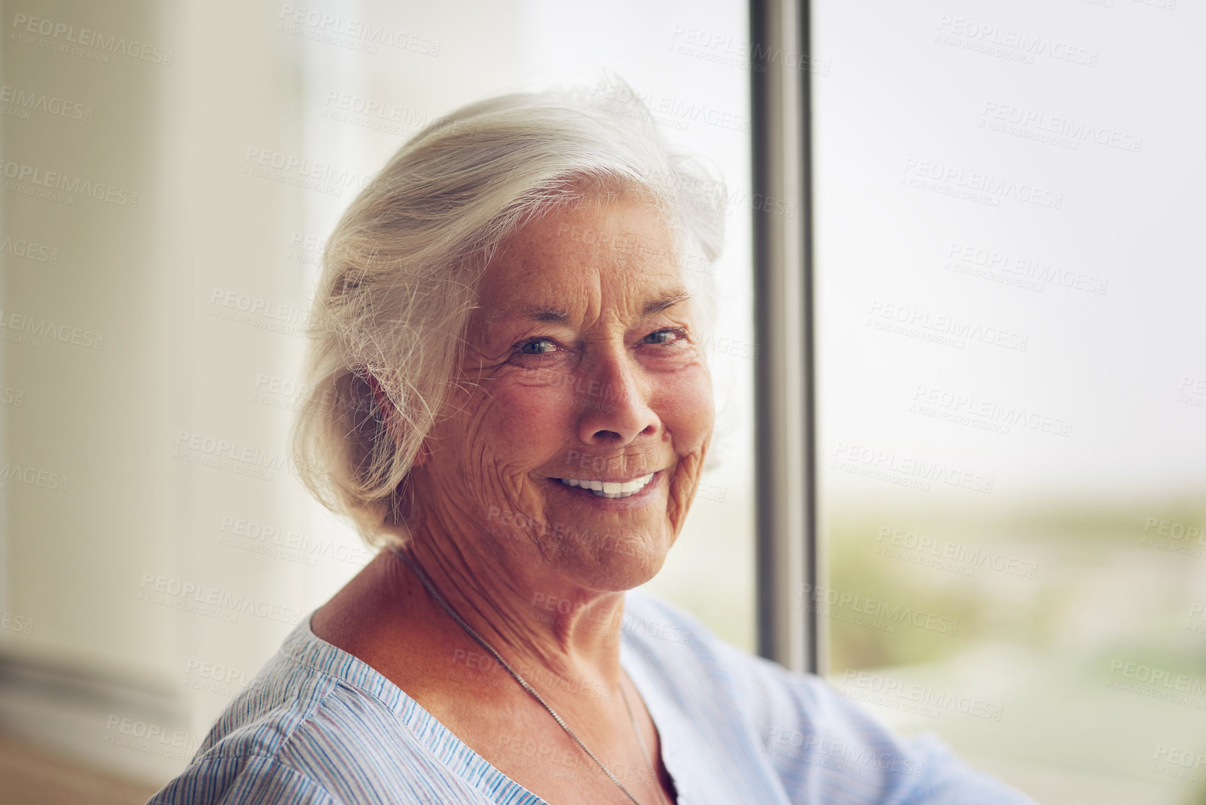 Buy stock photo Portrait of a happy and relaxed senior woman standing next to a window indoors