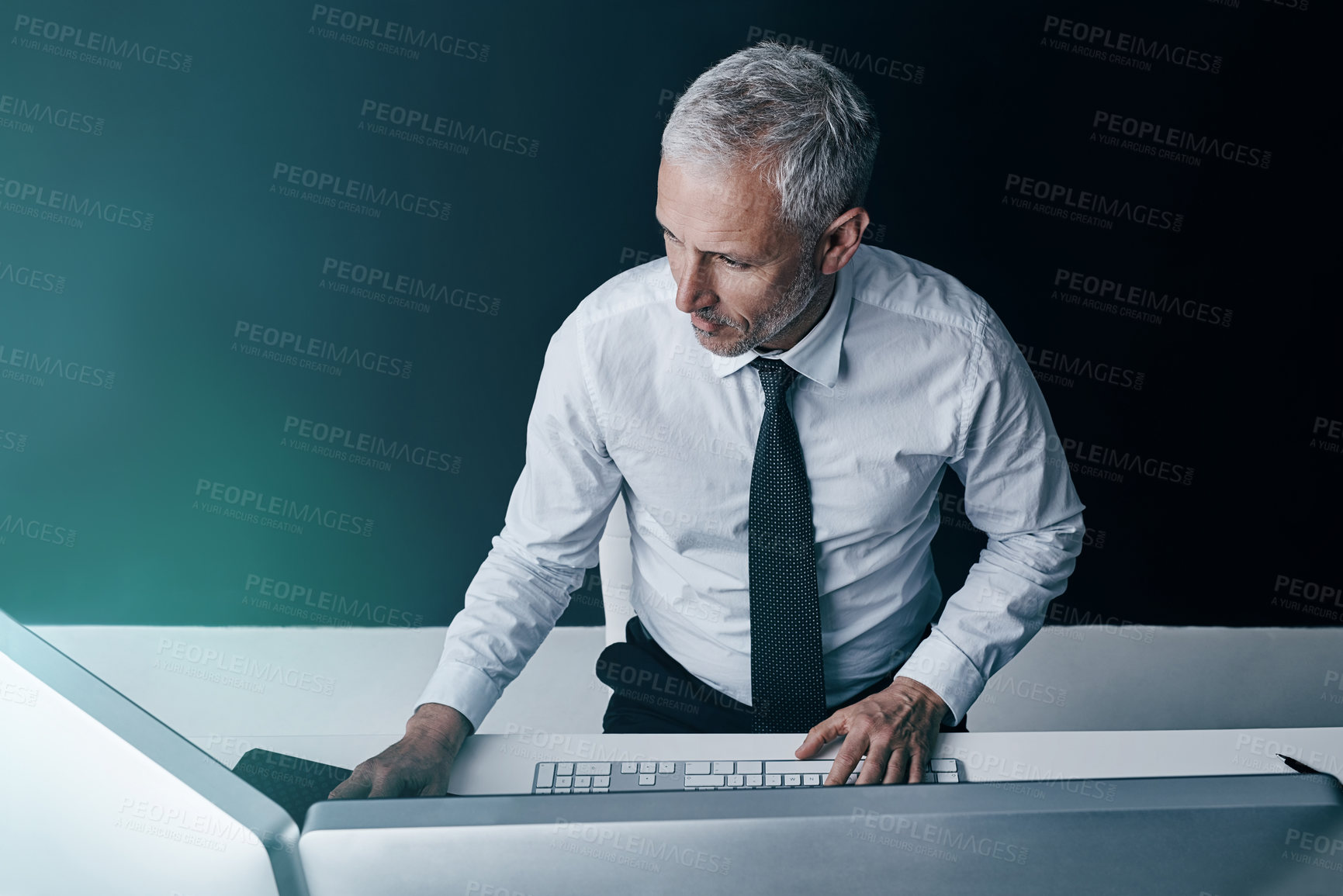 Buy stock photo High angle shot of a businessman working behind his computer in the office