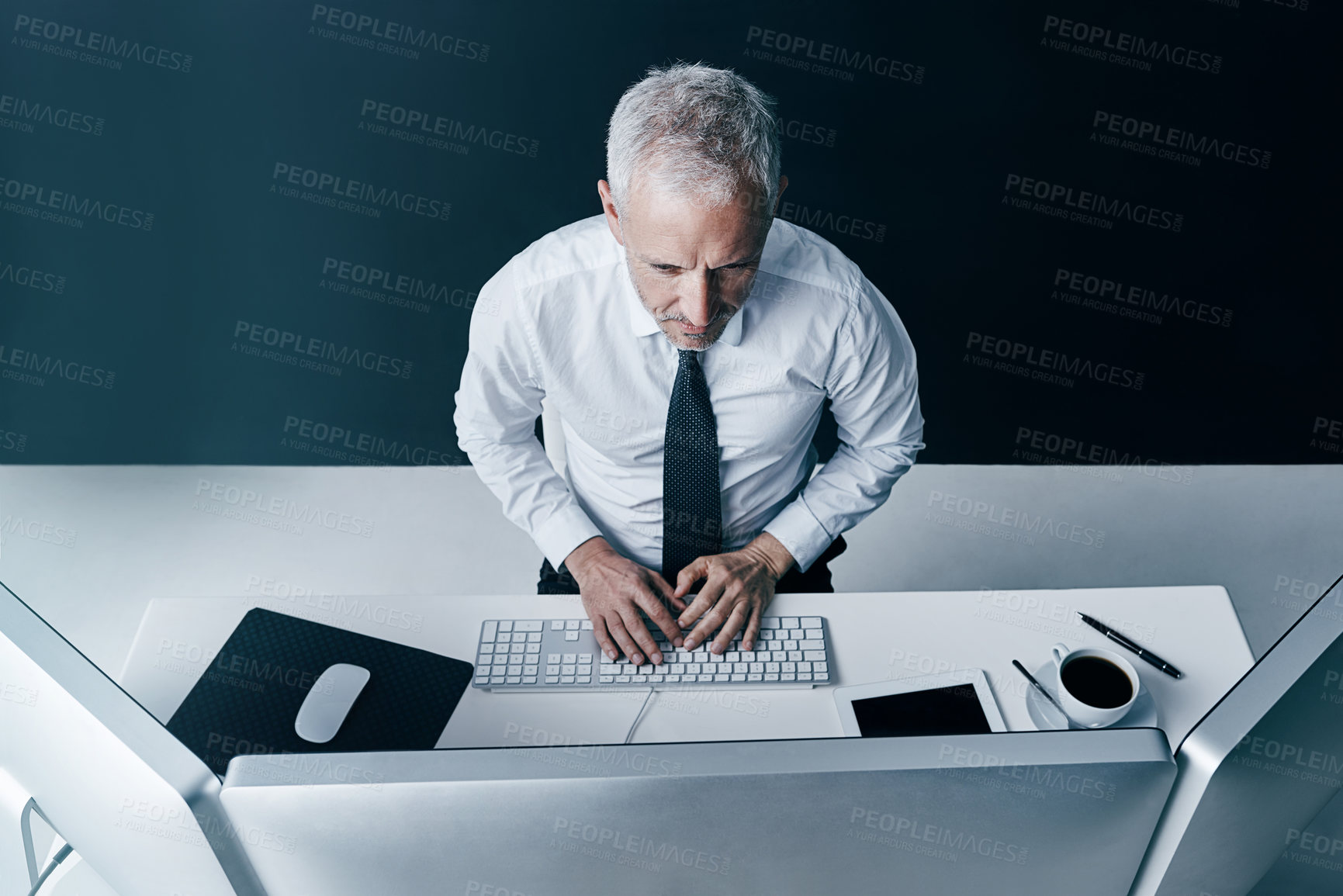 Buy stock photo High angle shot of a businessman working behind his computer in the office