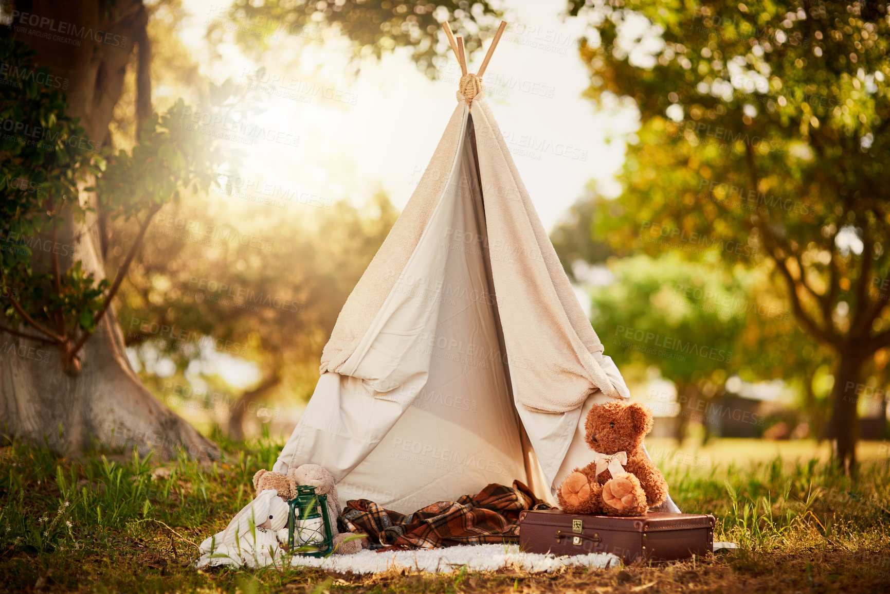 Buy stock photo Teepee, tent and fun in garden in nature outdoor at park for playing, camp and imagination of adventure. Cloth, shelter and fantasy house for background in forest with blanket, suitcase or teddy bear