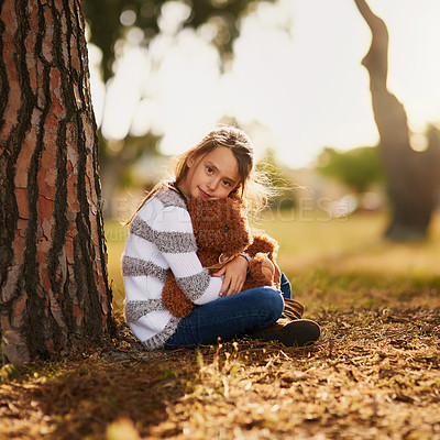 Buy stock photo Portrait of a sweet little girl hugging her teddy bear while playing outside