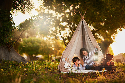 Buy stock photo Shot of two cute little siblings playing together in a teepee outside