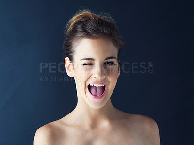 Buy stock photo Cropped shot of a beautiful young woman winking against a dark background