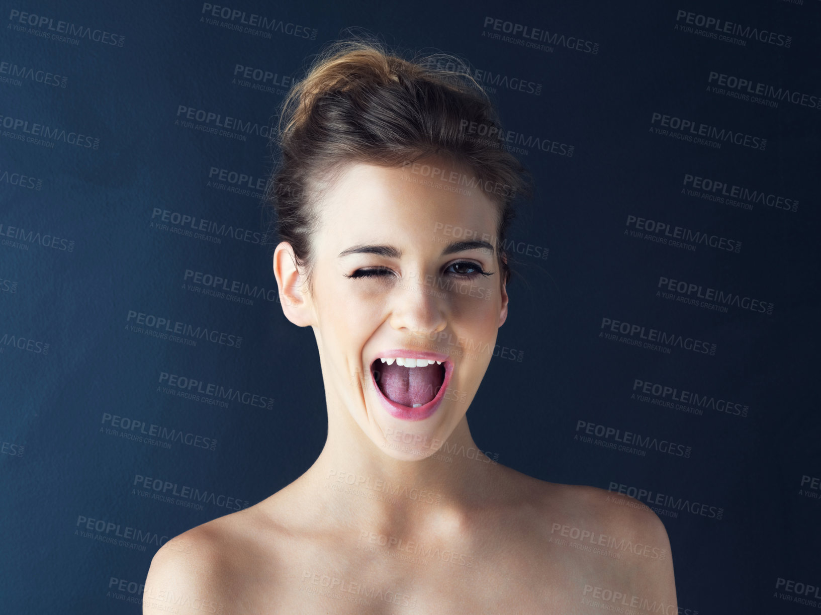 Buy stock photo Cropped shot of a beautiful young woman winking against a dark background