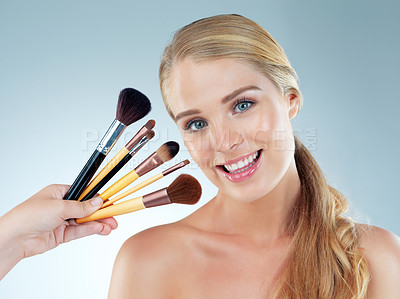 Buy stock photo Woman, portrait and smile with makeup brushes in studio for cosmetic, beauty and foundation of aesthetic. Female person, tools and salon for glamour, transformation and glow on blue background