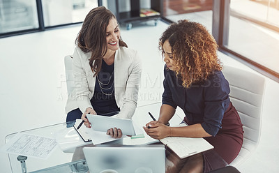 Buy stock photo Shot of two businesswomen discussing something on a digital tablet