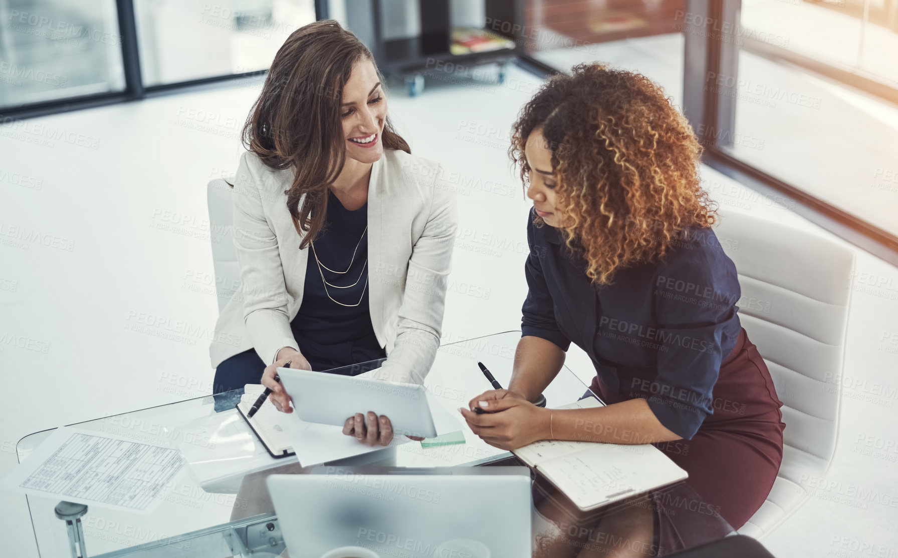 Buy stock photo Shot of two businesswomen discussing something on a digital tablet