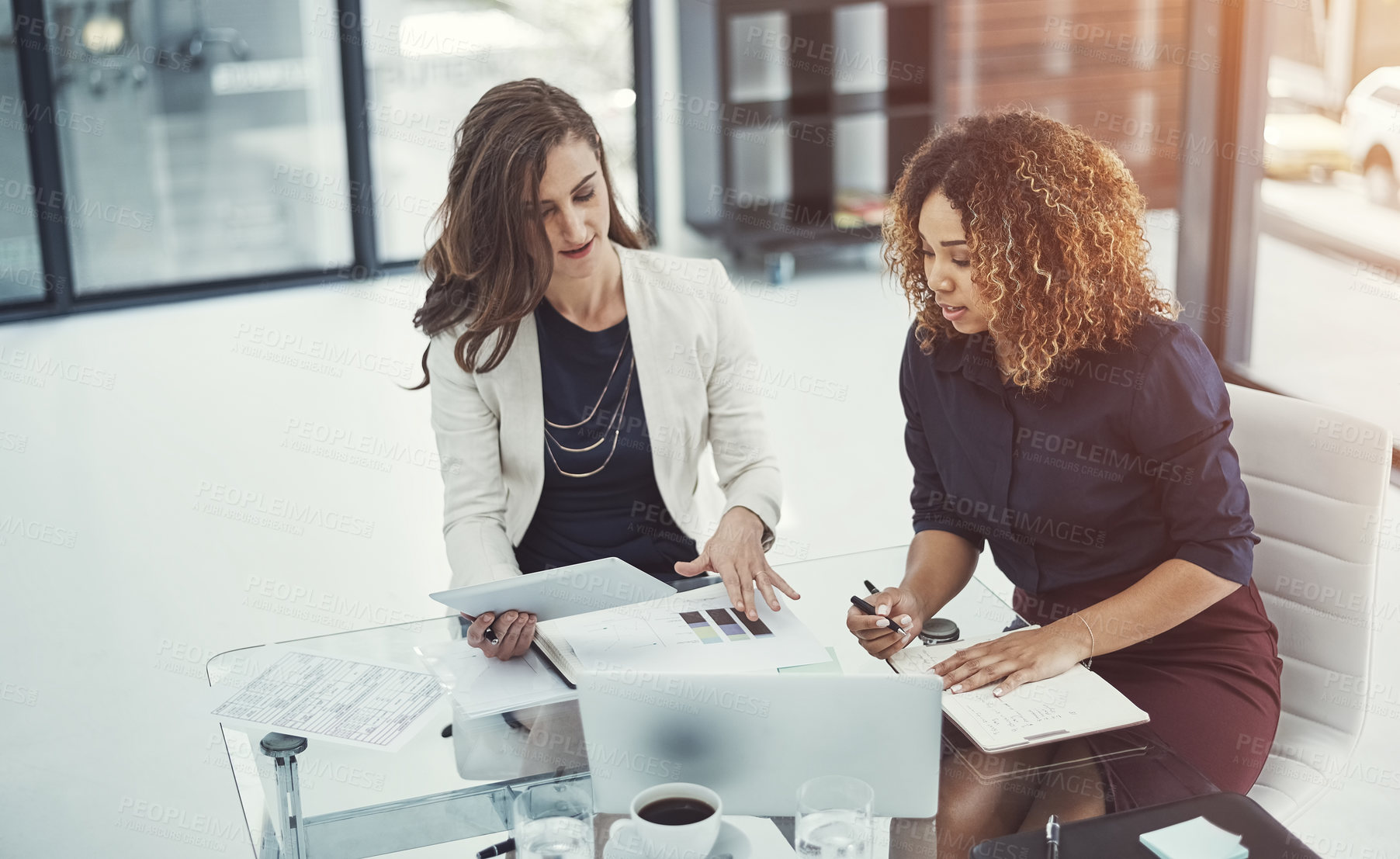 Buy stock photo Shot of two businesswomen discussing something on a digital tablet