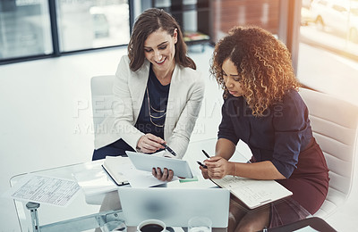 Buy stock photo Shot of two businesswomen discussing something on a digital tablet