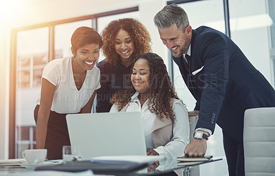 Buy stock photo Shot of a group of colleagues using a laptop together in a modern office