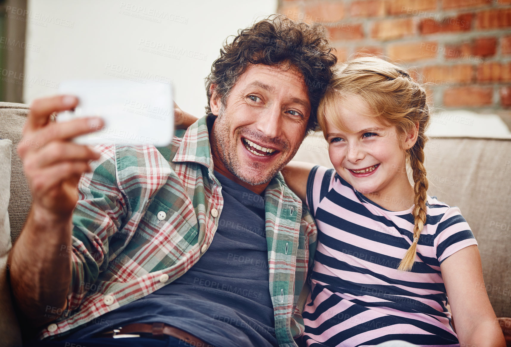 Buy stock photo Cropped shot of a father and his little daughter taking a selfie together at home