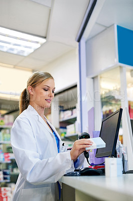 Buy stock photo Shot of a young pharmacist scanning a barcode on a product