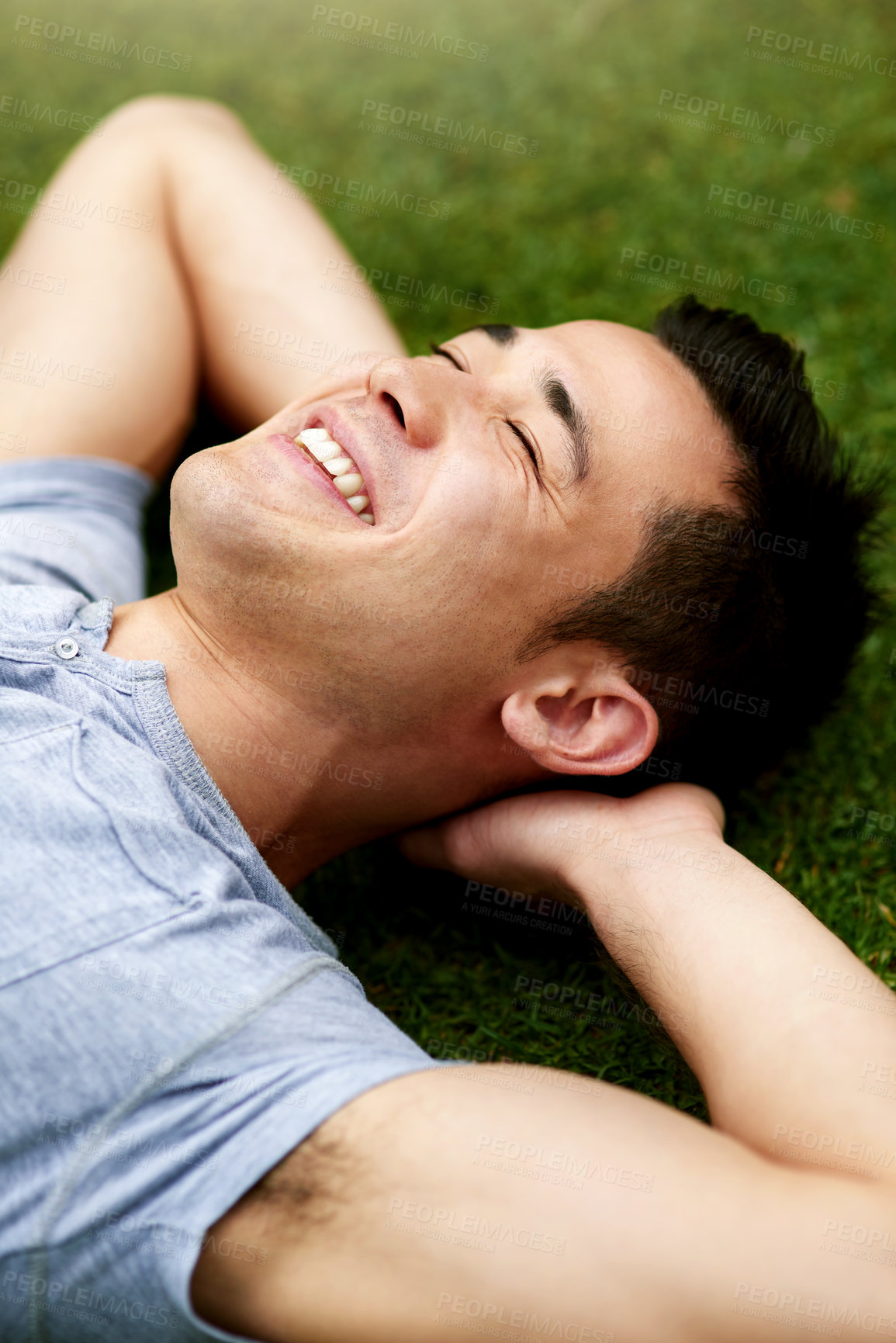 Buy stock photo Shot of a handsome young man relaxing on the grass outdoors