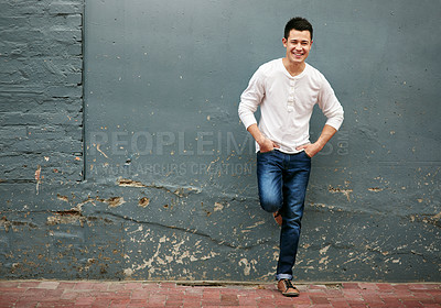 Buy stock photo Portrait of a handsome young man standing with his hands in his pockets against a grey wall