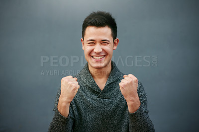 Buy stock photo Studio portrait of a handsome young man doing a fist pump against a grey background