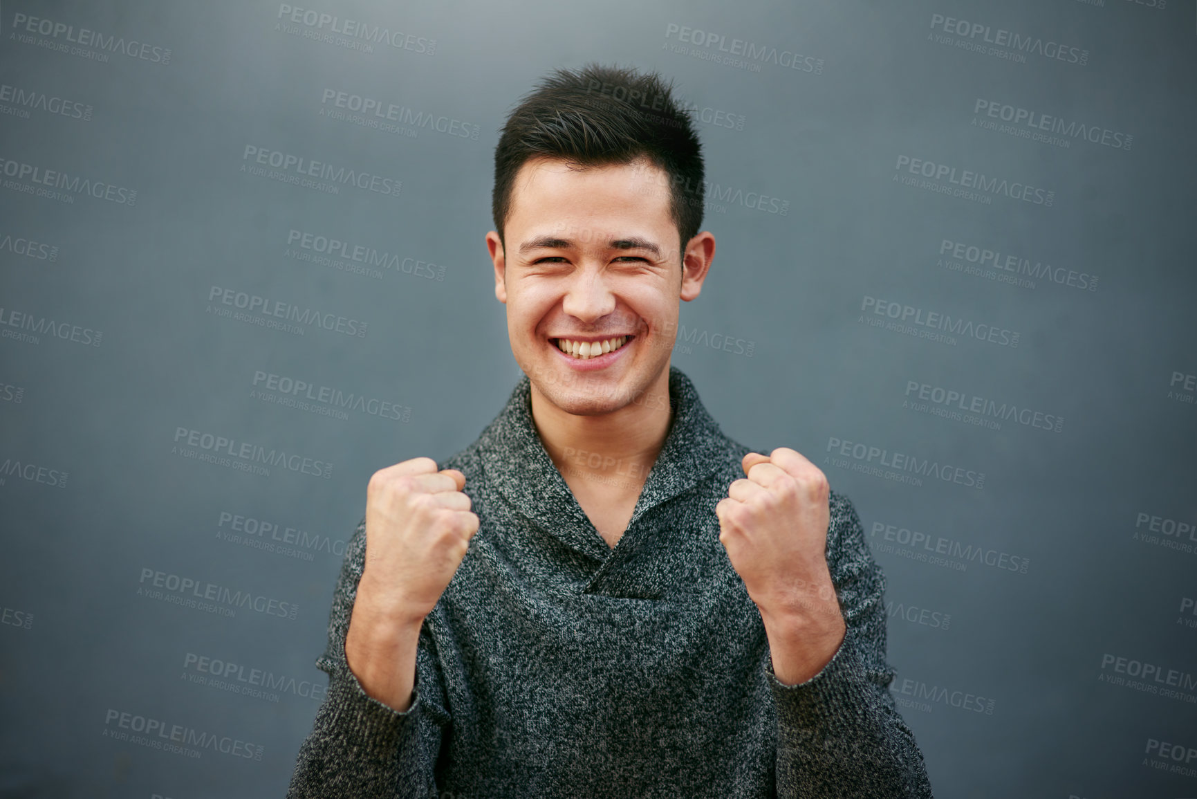 Buy stock photo Studio portrait of a handsome young man doing a fist pump against a grey background