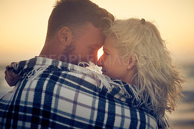 Buy stock photo Couple, hug and blanket at beach, sunset and eye contact for connection, bonding or relax with care, Man, woman and partner with embrace for smile, love or happy memory on vacation by sea in sunshine