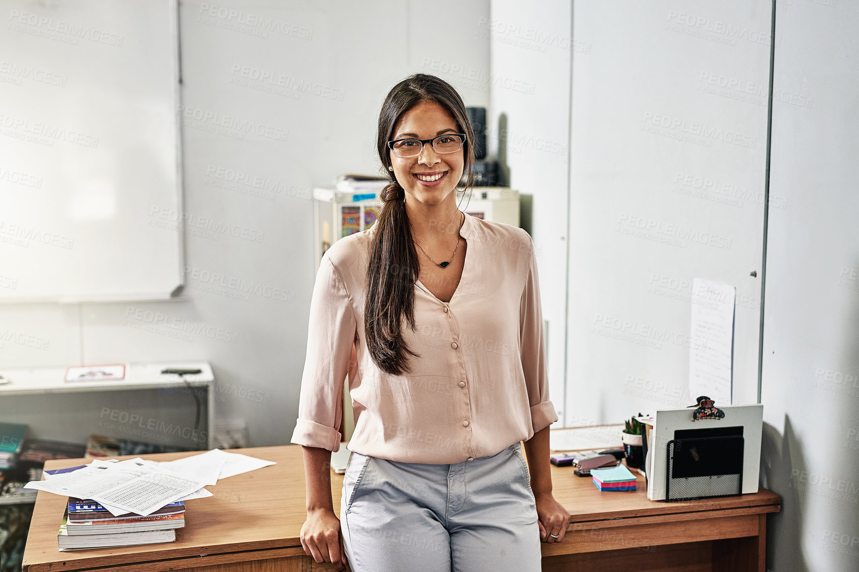 Buy stock photo Portrait, woman and teacher smile in school for education with glasses. Tutor, educator and desk or office for learning, knowledge or professional study in development classroom with happiness