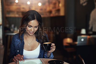 Buy stock photo Shot of a relaxed young woman using her tablet in a coffee shop