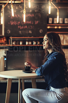 Buy stock photo Shot of a relaxed young woman enjoying a cup of coffee in a coffee shop