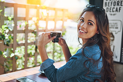 Buy stock photo Portrait of a happy young woman enjoying a cup of coffee in a coffee shop