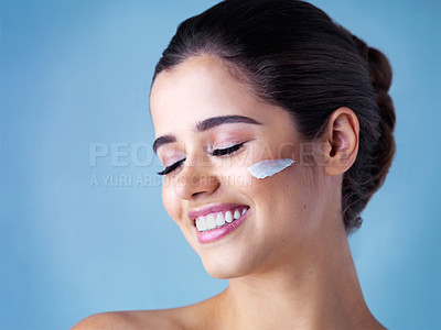 Buy stock photo Woman, smile and skincare moisturizer in studio with lotion cream for dermatology, blue background or treatment. Female person, model and facial cosmetics with sunscreen protection, relax or hygiene