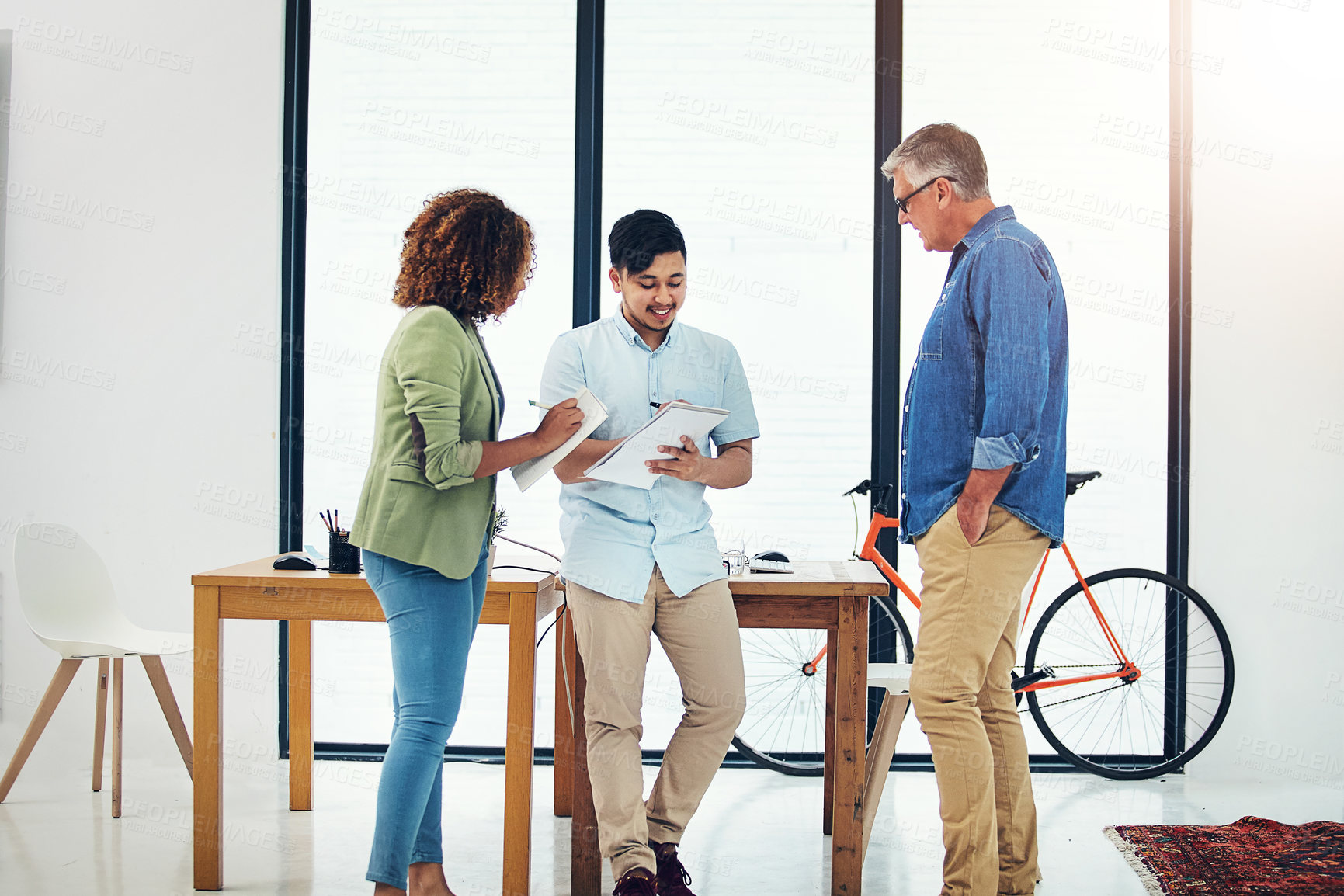 Buy stock photo Shot of a creative entrepreneur offering advice to two new colleagues in the office