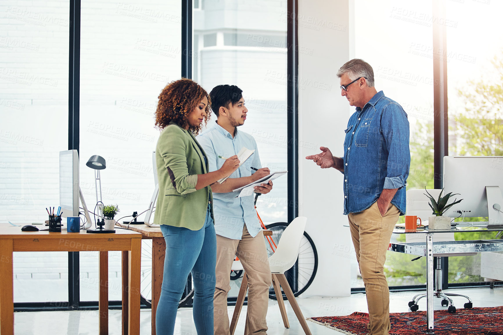 Buy stock photo Shot of a creative entrepreneur offering advice to two new colleagues in the office