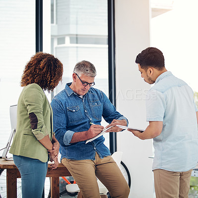 Buy stock photo Shot of a creative entrepreneur offering advice to two new colleagues in the office