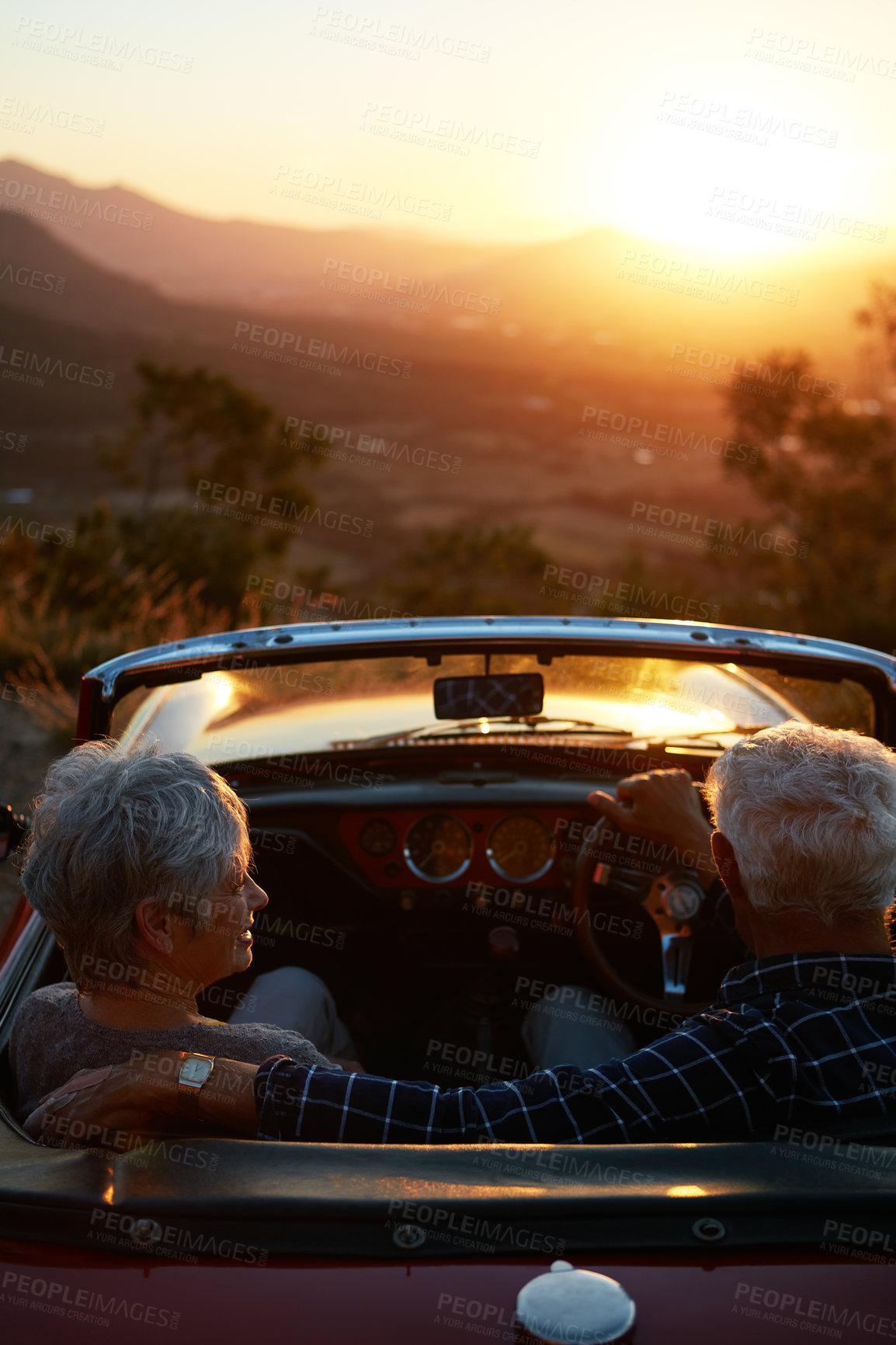 Buy stock photo Shot of an affectionate senior couple enjoying the sunset during a roadtrip