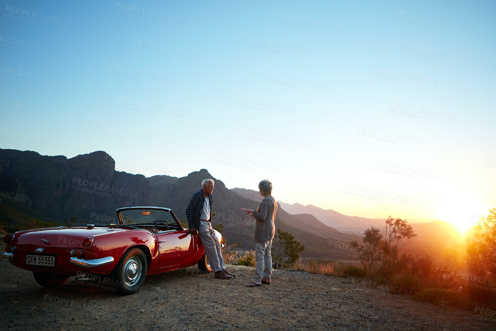 Buy stock photo Shot of an affectionate senior couple enjoying the sunset during a roadtrip