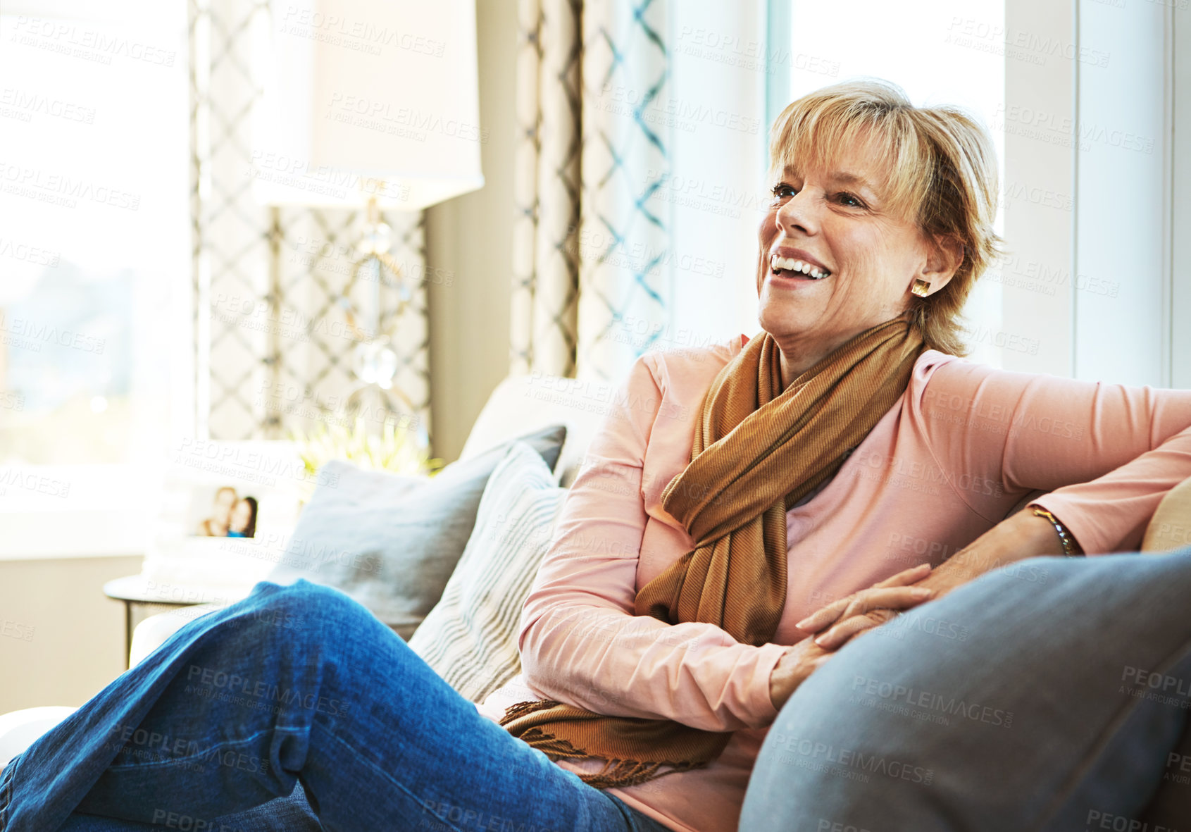 Buy stock photo Thinking, laugh or mature woman on couch to relax with freedom on living room sofa at home. Funny joke, happy or senior person with smile, peace or wellness in retirement, lounge or house for resting