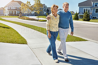 Buy stock photo Shot of a happy senior couple waking around their neighborhood together