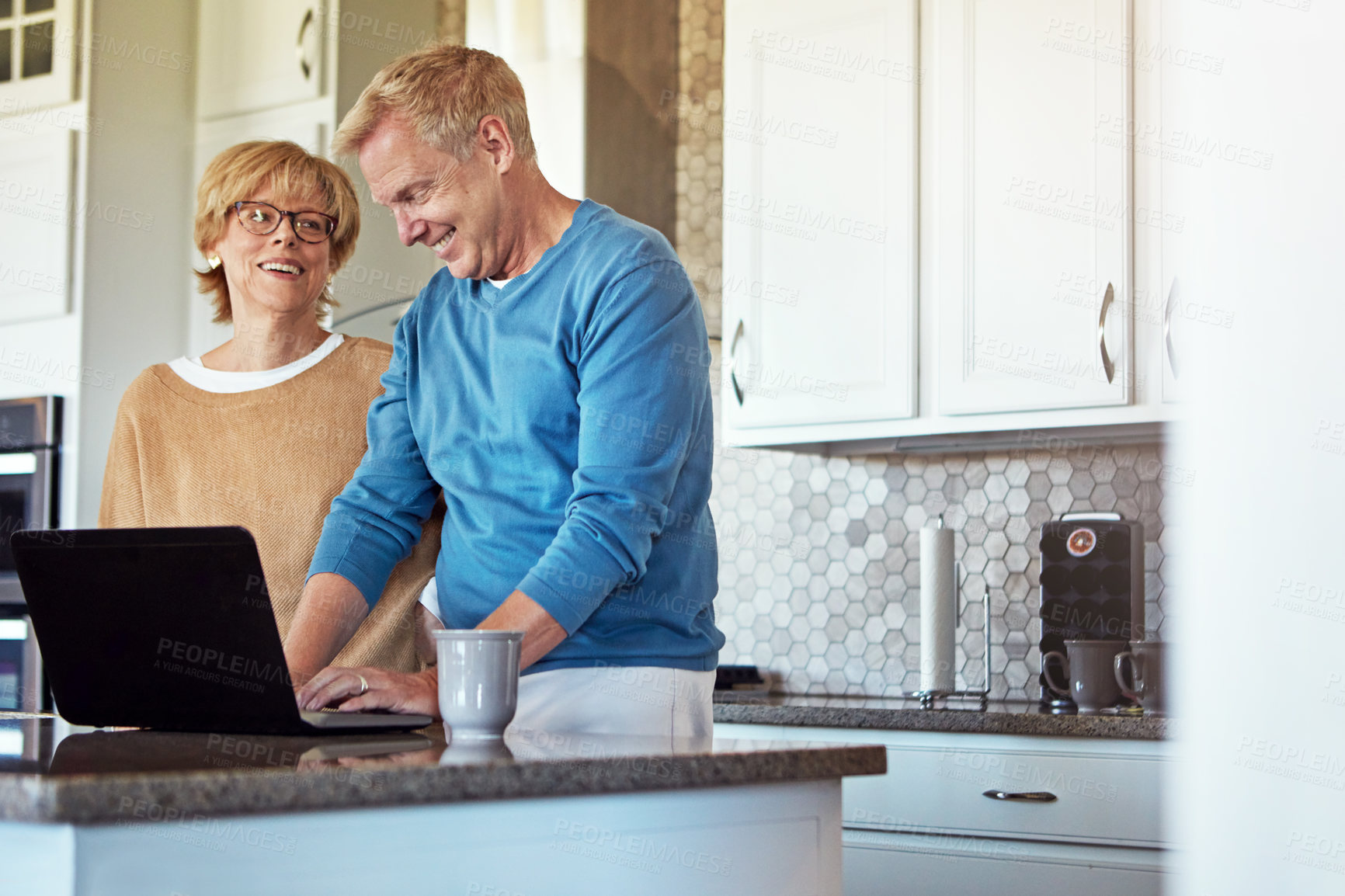 Buy stock photo Cropped shot of a mature couple using their laptop in the kitchen