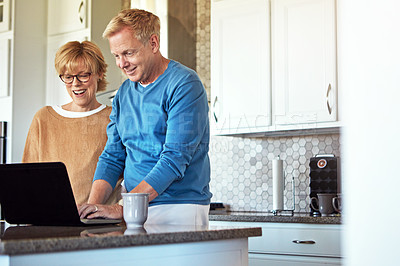 Buy stock photo Cropped shot of a mature couple using their laptop in the kitchen