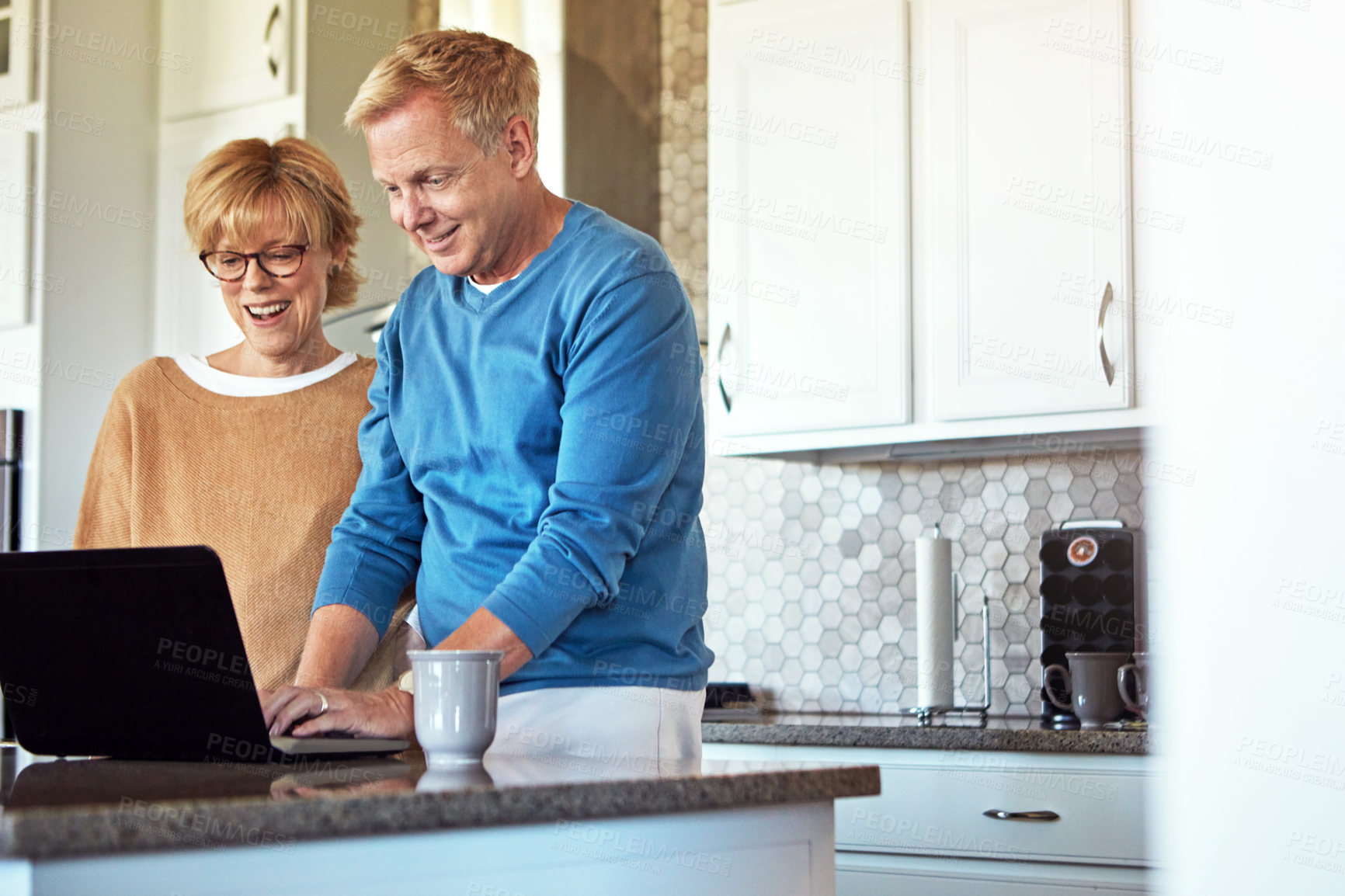 Buy stock photo Cropped shot of a mature couple using their laptop in the kitchen