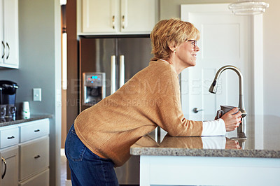 Buy stock photo Cropped shot of a mature woman drinking coffee in her kitchen