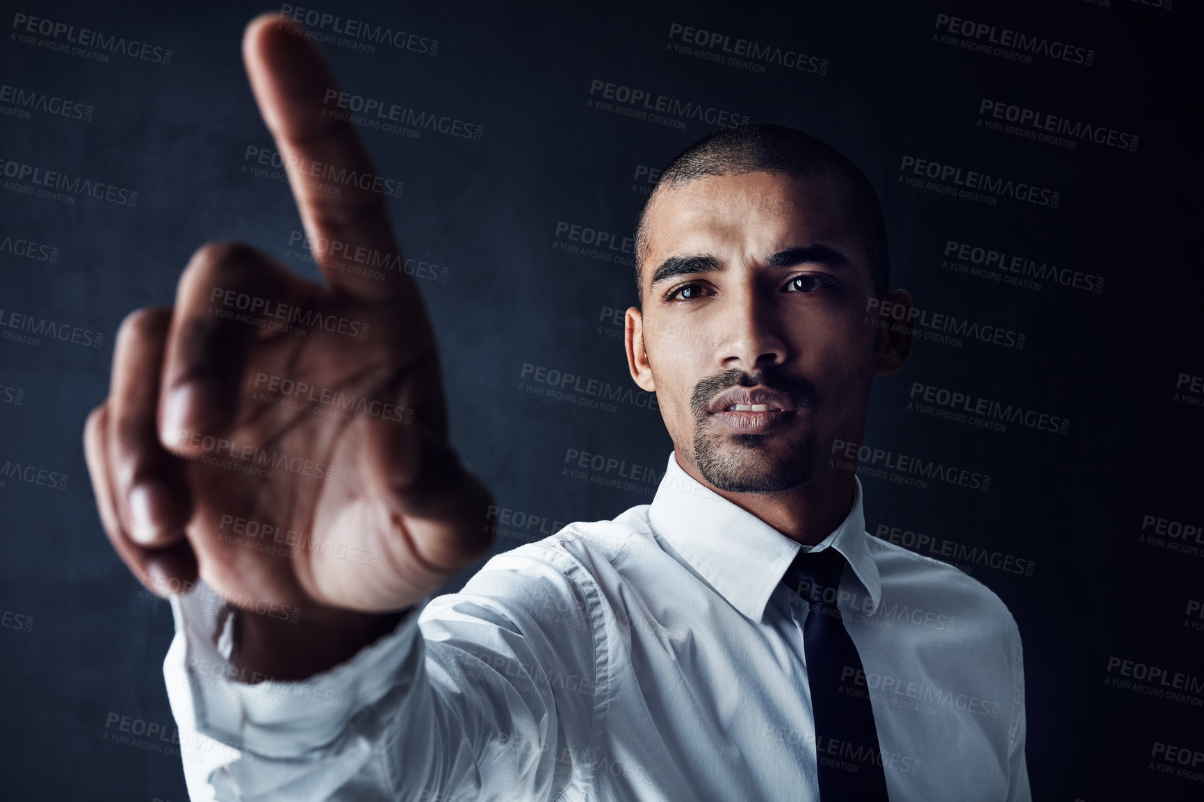 Buy stock photo Studio shot of a young businessman connecting to a user interface with his finger against a dark background