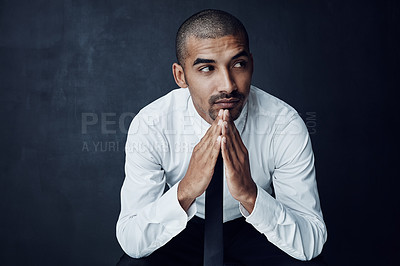 Buy stock photo Studio shot of a young businessman looking thoughtful against a dark background